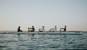 Unterschiedliche Menschen sintzen gemeinsam in einem Boot auf offener See.